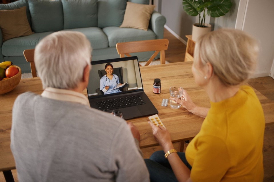 Older couple at their kitchen table on a video visit with a provider