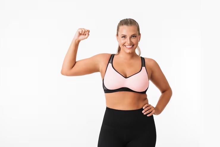 Smiling woman in workout clothes flexing her arm